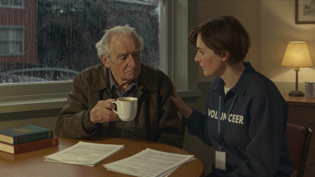 Volunteer sitting quietly with an elderly man sharing tea in a community center.